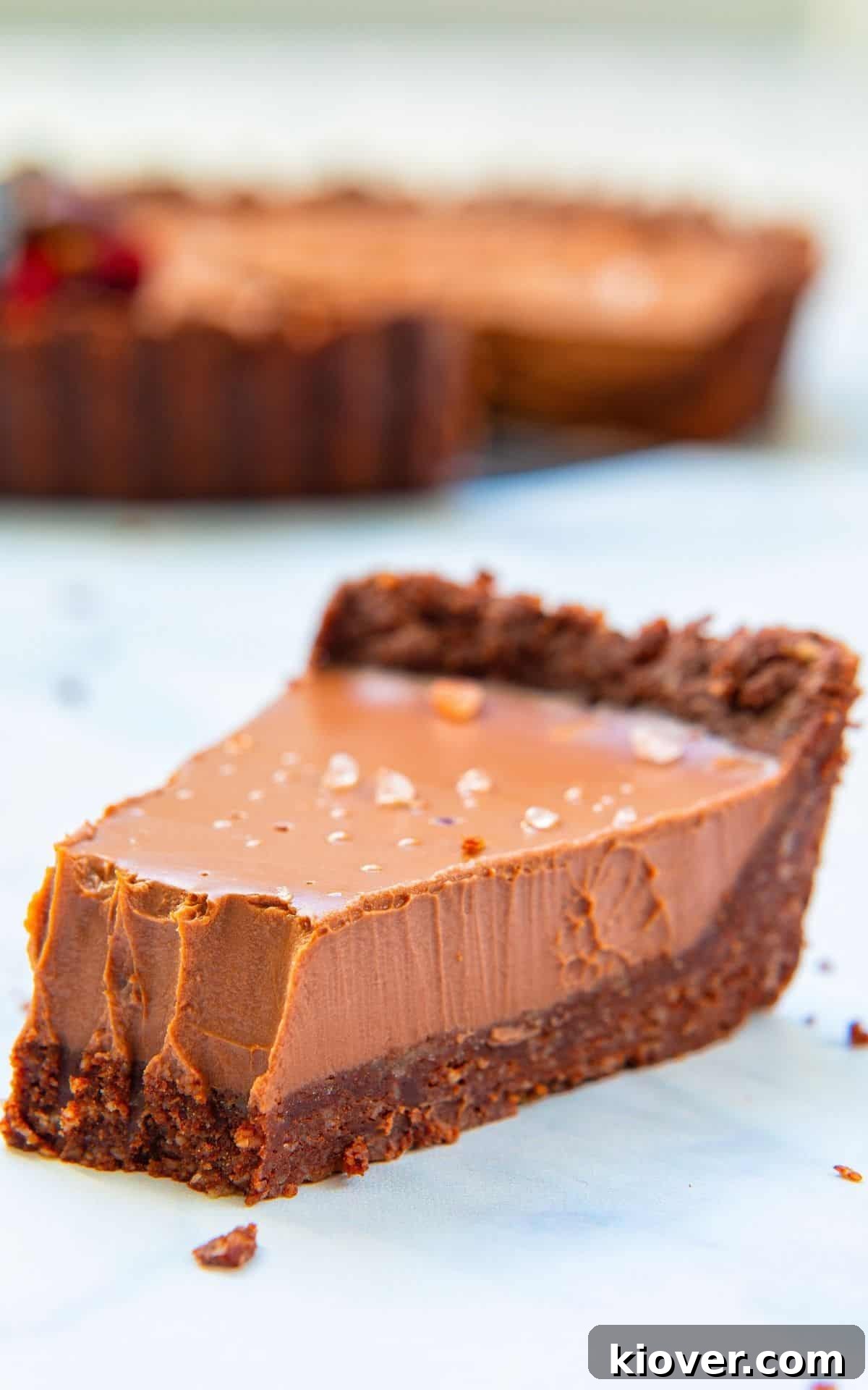Close up of a sliced vegan chocolate tart from front angle with a bite taken.