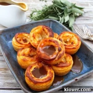 Gluten-Free Vegan Yorkshire Puddings Recipe 13 Yorkshire puddings towered on a blue/black plate covered in gravy.