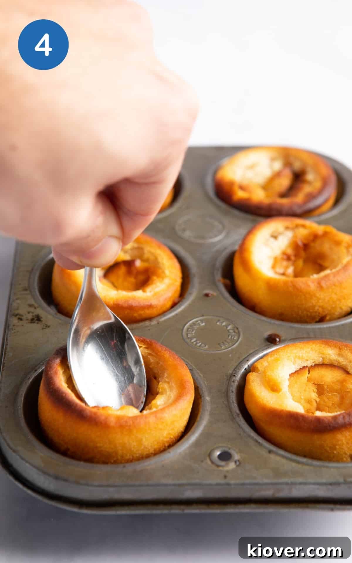 Gluten-Free Vegan Yorkshire Puddings Recipe 7 spoon being pressed into the centre of cooked Yorkshire puddings.