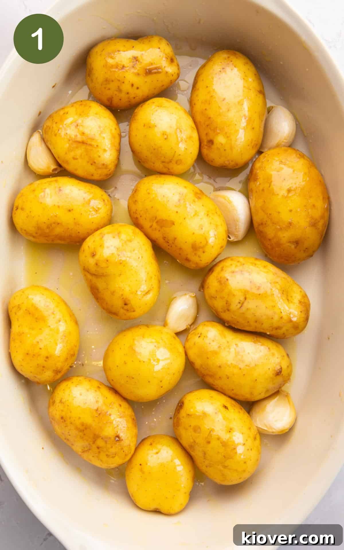 Crispy Smashed Potatoes with Garlic and Parmesan 4 baby potatoes, garlic cloves, vinegar and olive oil in a baking dish.
