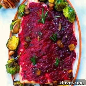 Festive Baked Salmon for Christmas Dinner 12 baked christmas salmon served with cranberry sauce an brussels sprouts on a white plate.