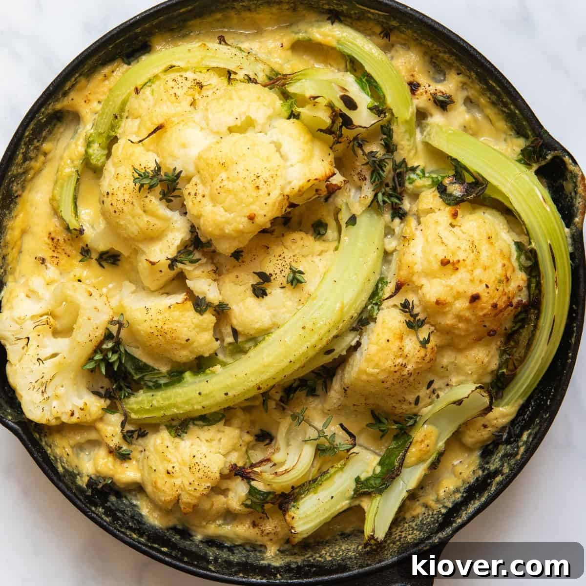 Cooked cauliflower cheese in black pan on white background 