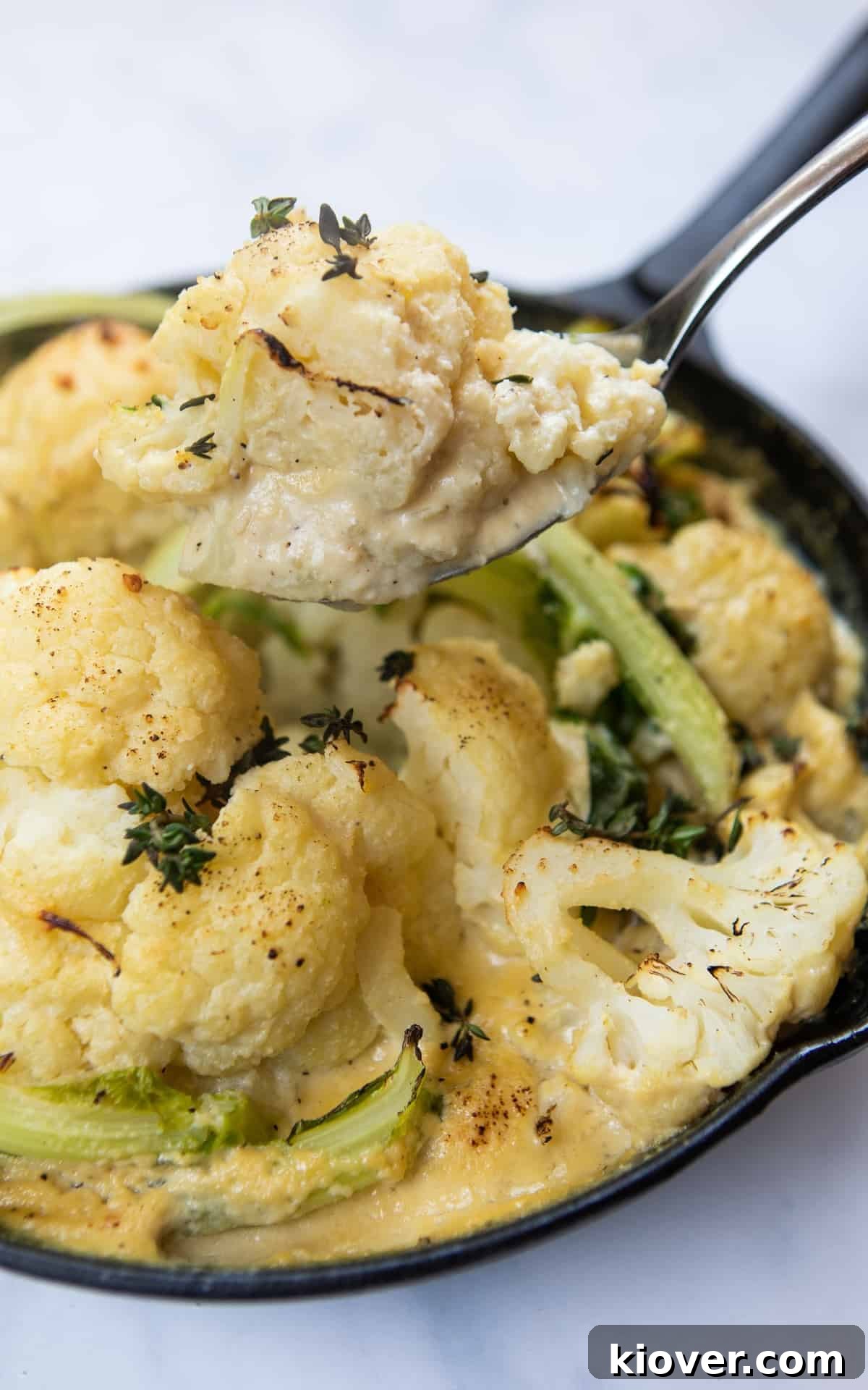 Cauliflower cheese being served on a spoon 