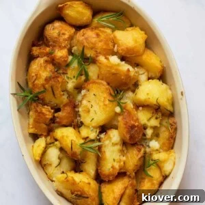 rosemary infused roast potatoes in a baking dish on a white marble background.