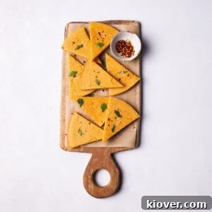 Crispy Socca Chickpea Pancake Recipe for Beginners 8 Socca flatbread slices into triangles, served on a wooden board.