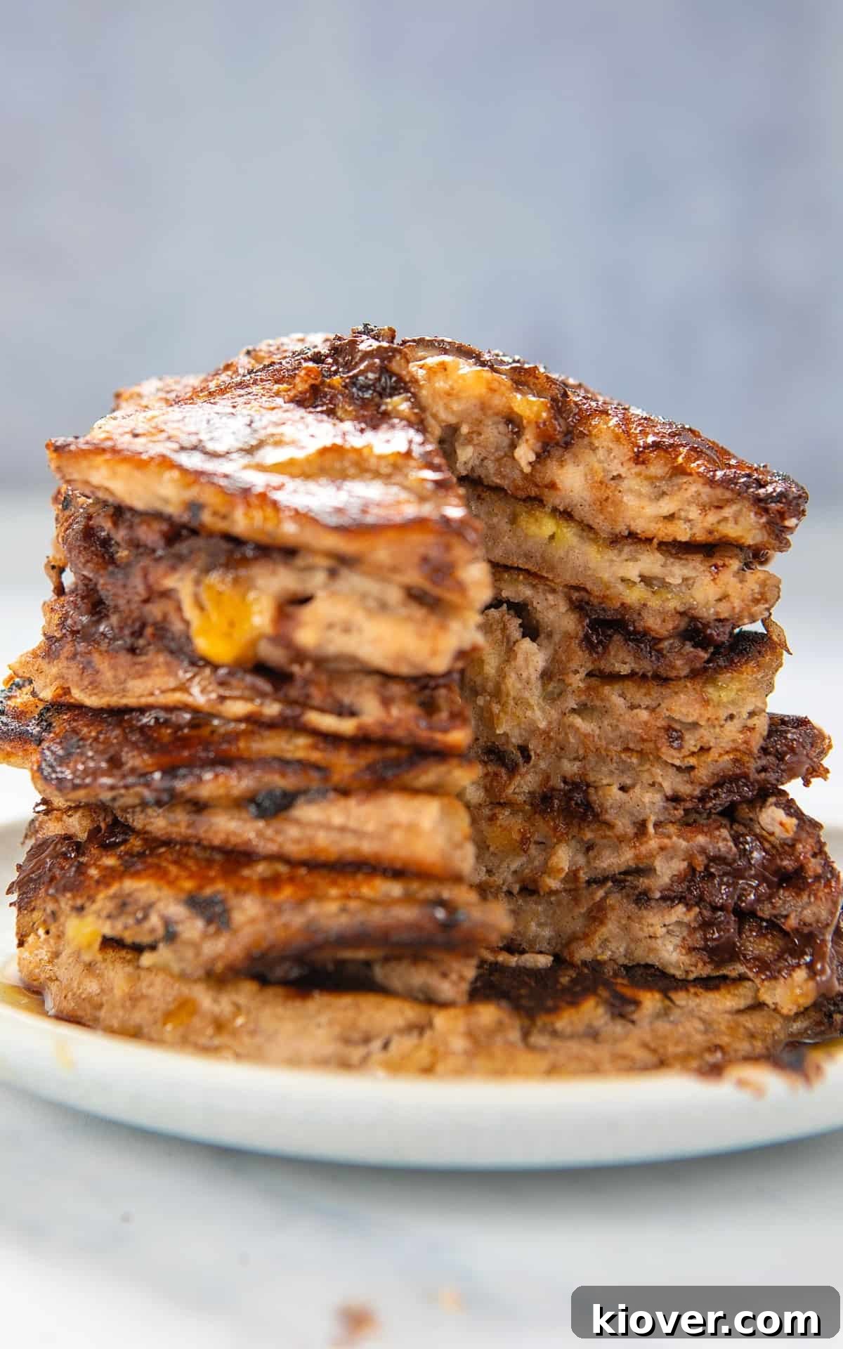8 banana pancakes stacked on a white place cut open to see inside.