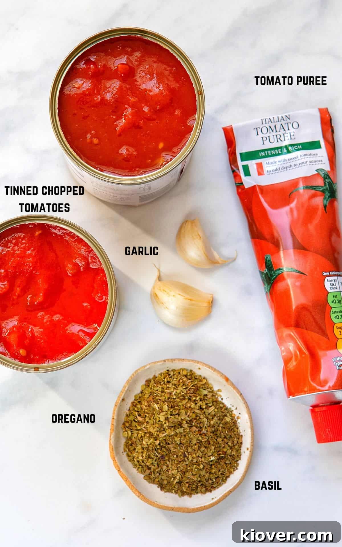 ingredients for homemade pizza sauce on a marble background.