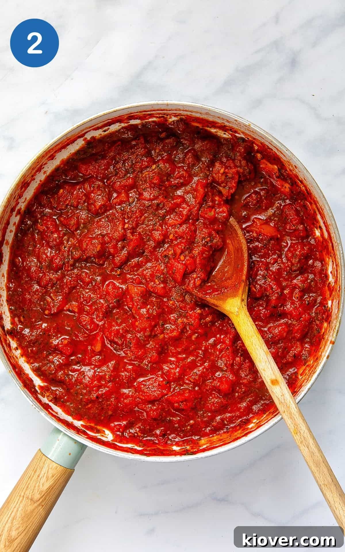 pizza sauce cooked in a pot with a wooden spoon showing.