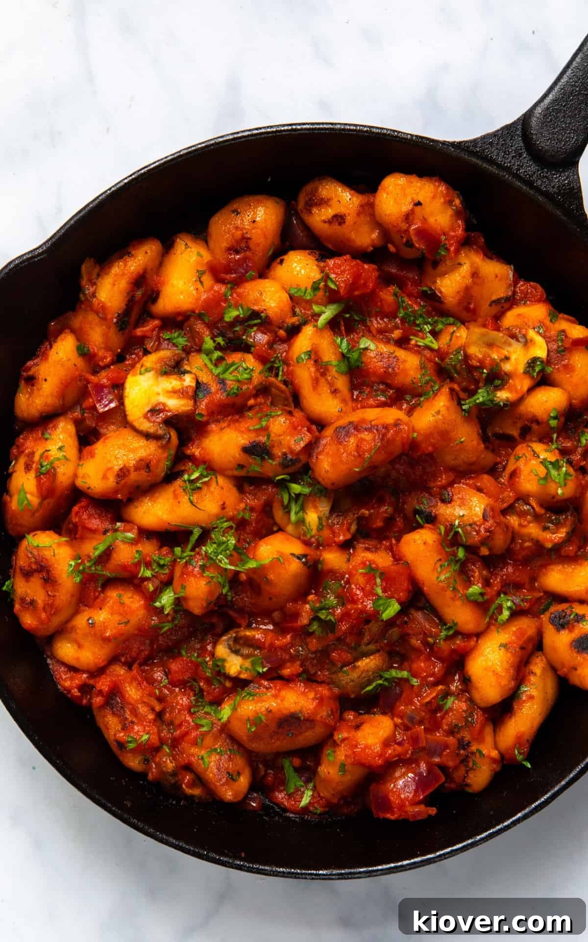 Sweet Potato Gnocchi Recipe: Light, Fluffy & Flavorful 11 Sweet Potato Gnocchi in a large frying pan with sauce. Frying pan is on white marble background.