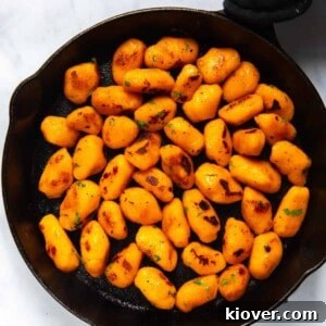 Sweet Potato Gnocchi Recipe: Light, Fluffy & Flavorful 16 Sweet Potato Gnocchi in black frying pan. Pan is displayed on white background.