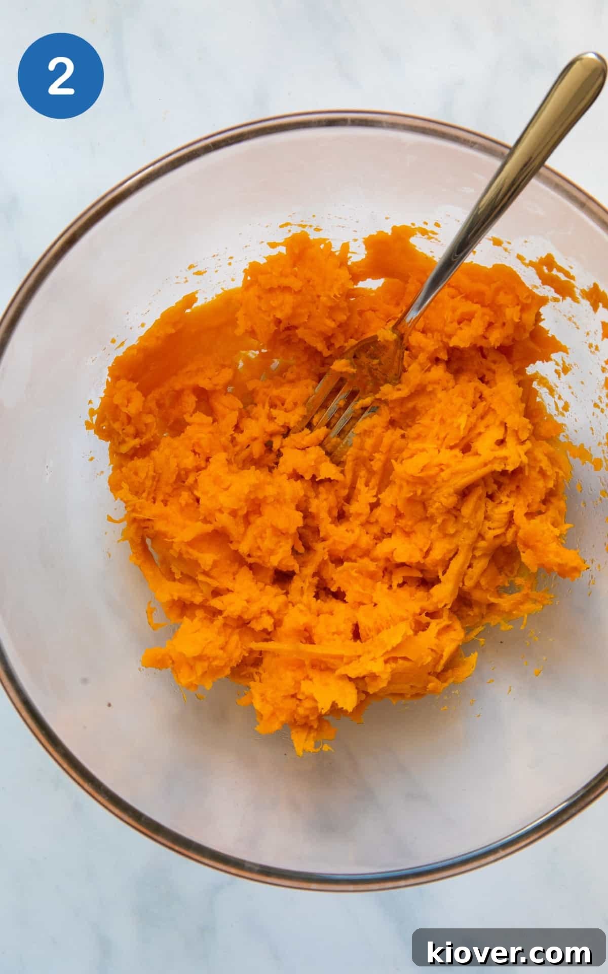 Sweet Potato Gnocchi Recipe: Light, Fluffy & Flavorful 5 Sweet potato flesh being mashed in a large mixing bowl presented on white background.