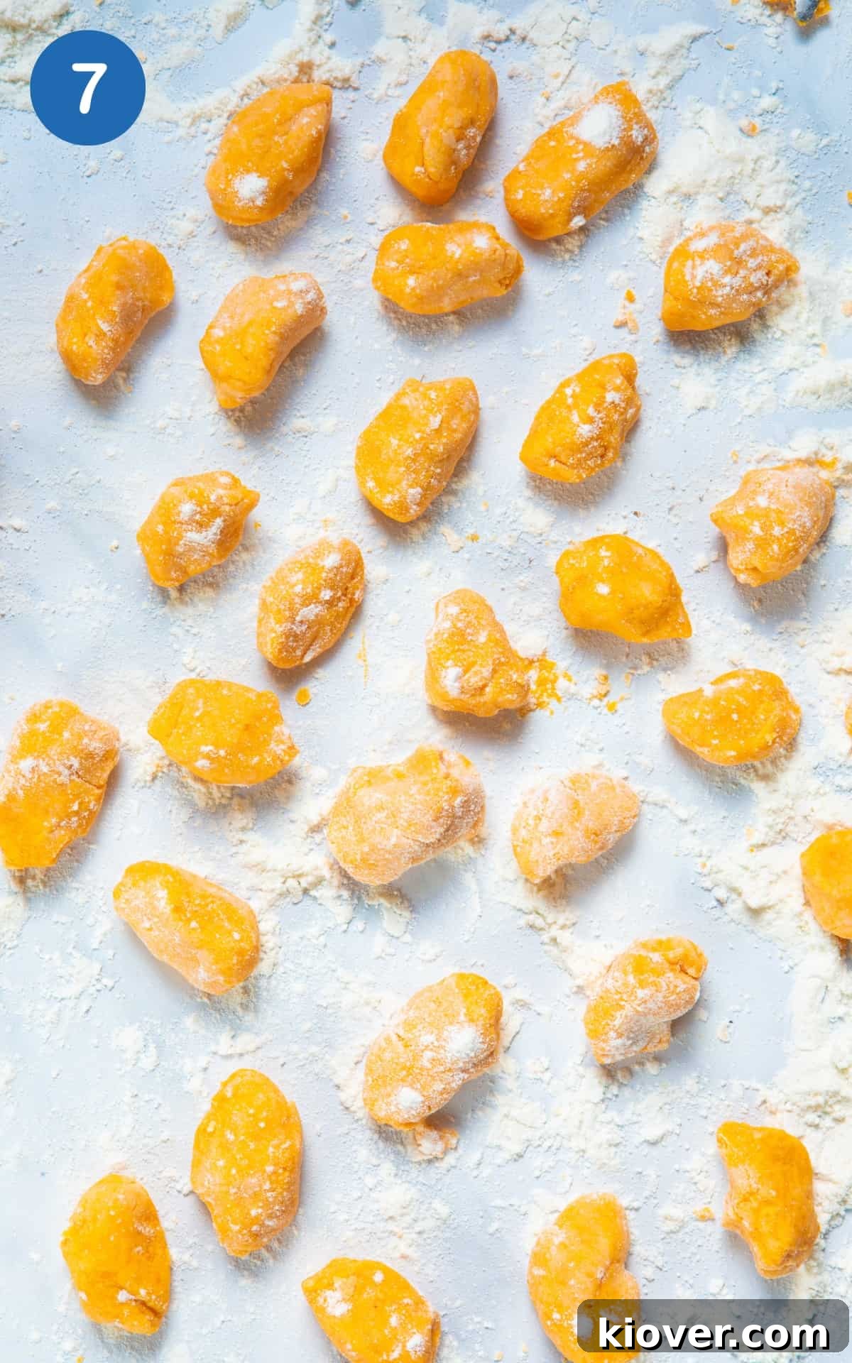 Sweet Potato Gnocchi Recipe: Light, Fluffy & Flavorful 10 Sweet potato gnocchi balls rolled up on white surface with flour.