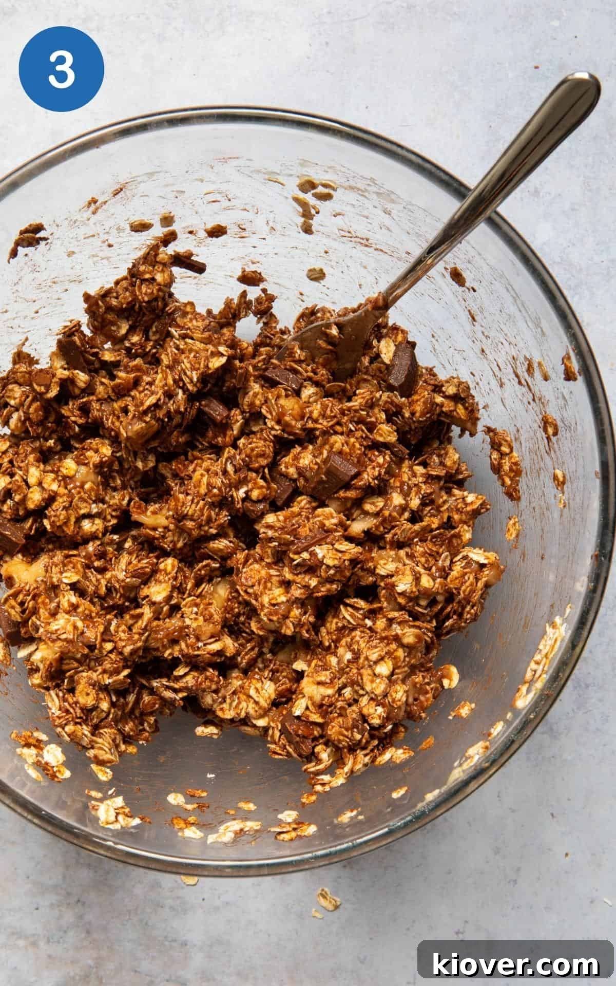 Chocolate flapjack mixture being mixed together in large mixing bowl.