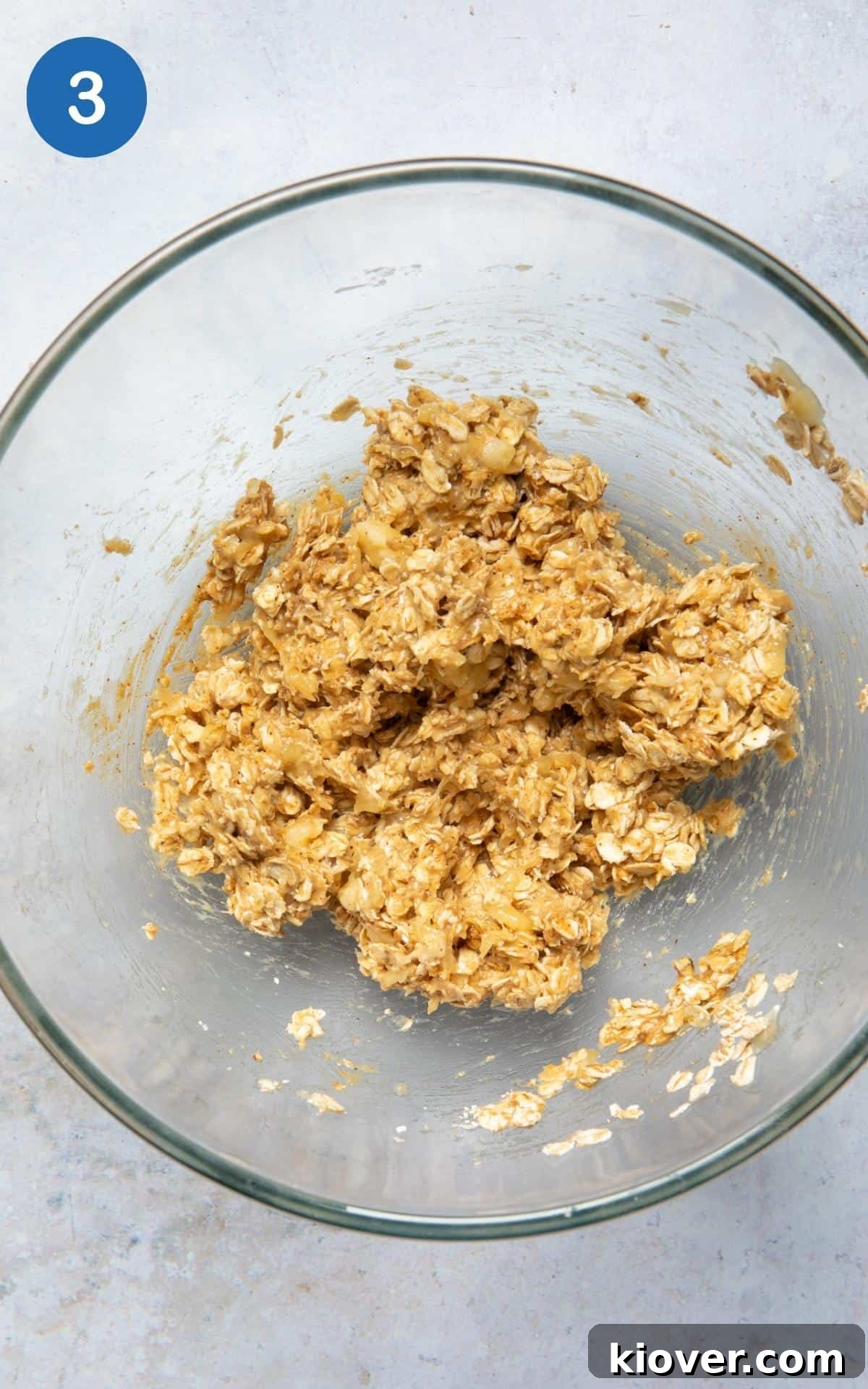 Ingredients to make oat cookies being combined in large mixing bowl on white background.