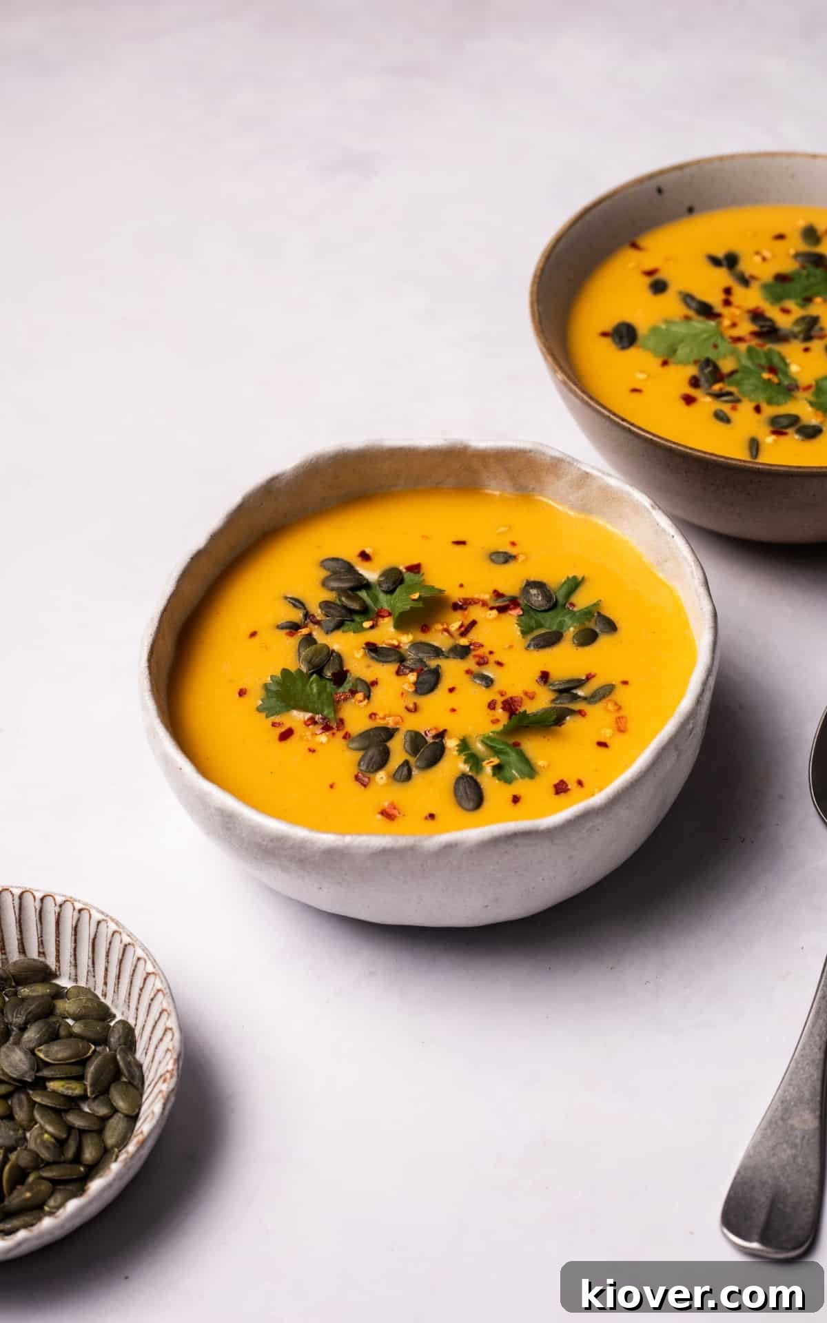 Creamy Pumpkin & Butternut Soup Recipe for Fall Comfort 7 Pumpkin and Butternut Soup topped with chilli flakes and pumpkin seeds.