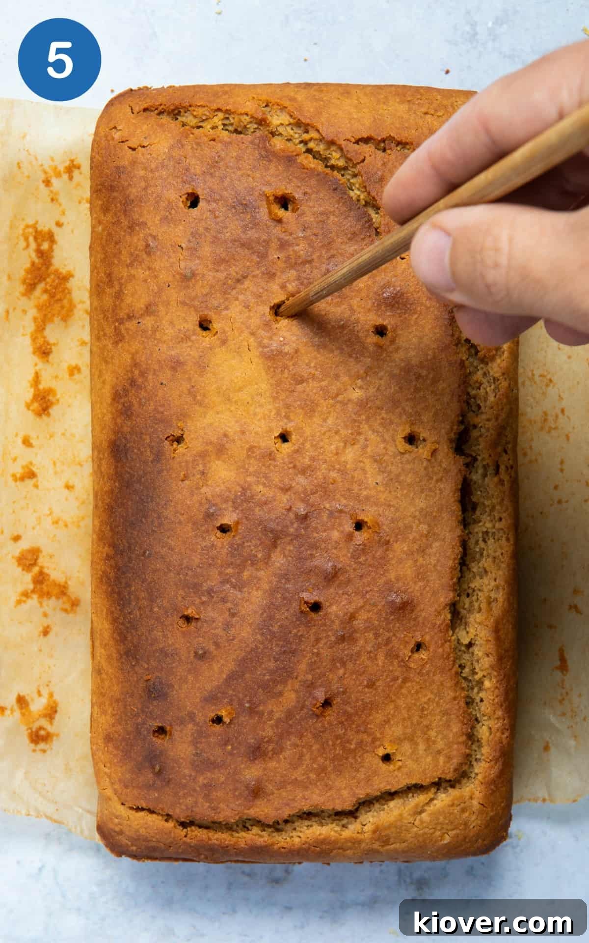 Vegan Lemon Drizzle Cake Recipe — Light Citrus Loaf 8 holes being created in lemon drizzle cake with chopstick.