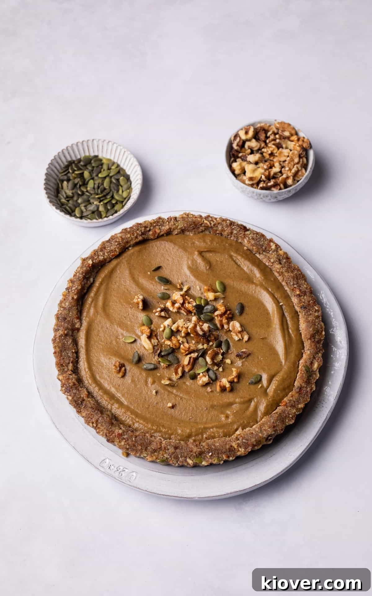 No Bake Pumpkin Pie decorated with pumpkin seeds and walnuts on top.