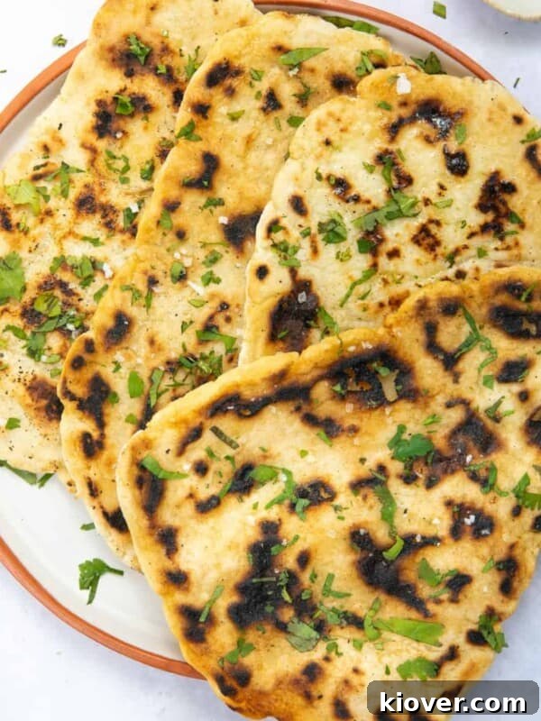Gluten free naan bread on a plate displayed on white background.