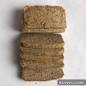 Overhead shot of sliced seeded bread on white surface.