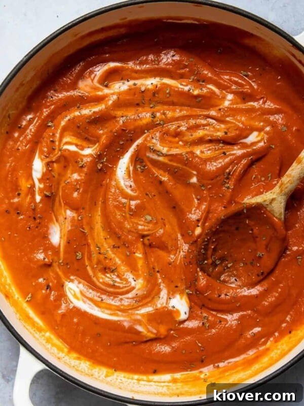 Tomato soup in a large pot with a wooden spoon.