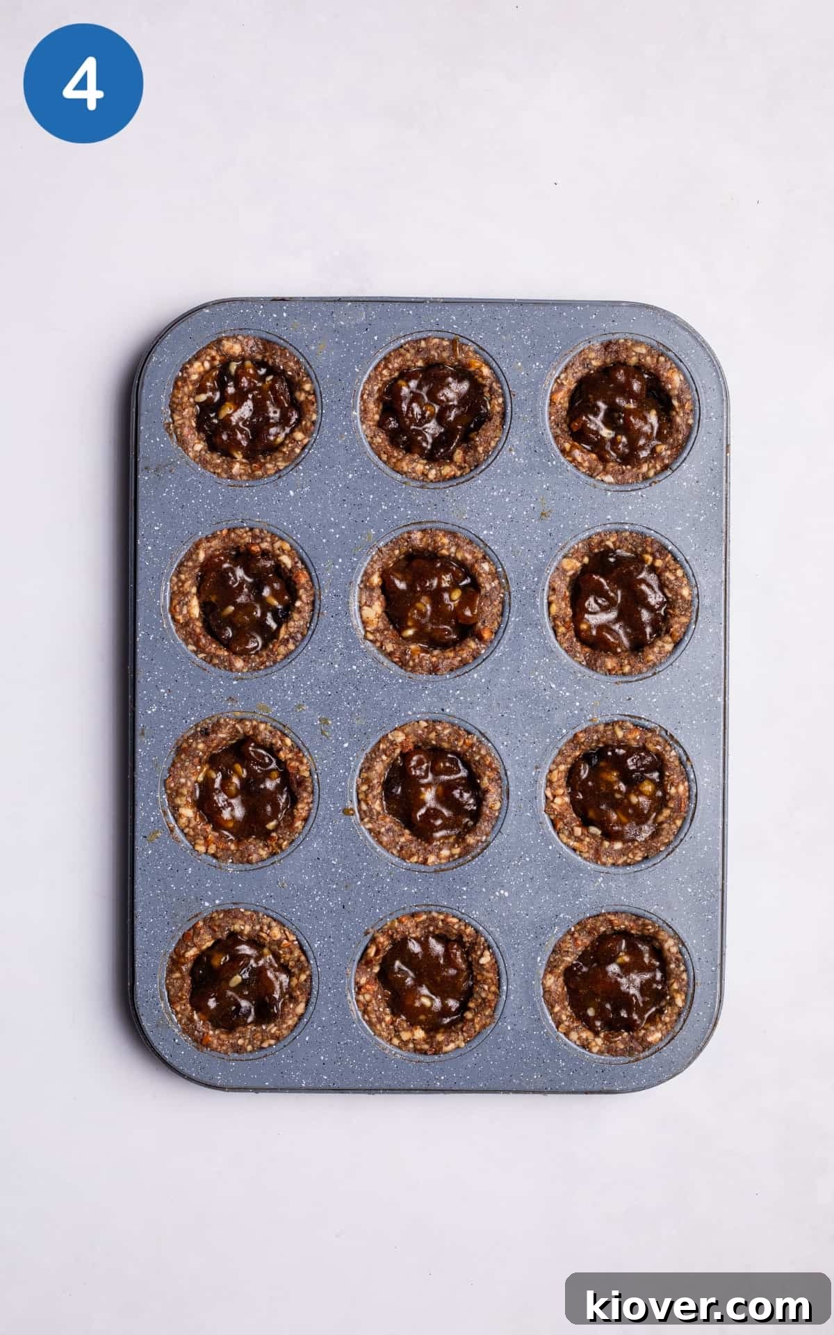 Adding a spoon of mince pie mix into the middle of nut base mixture.